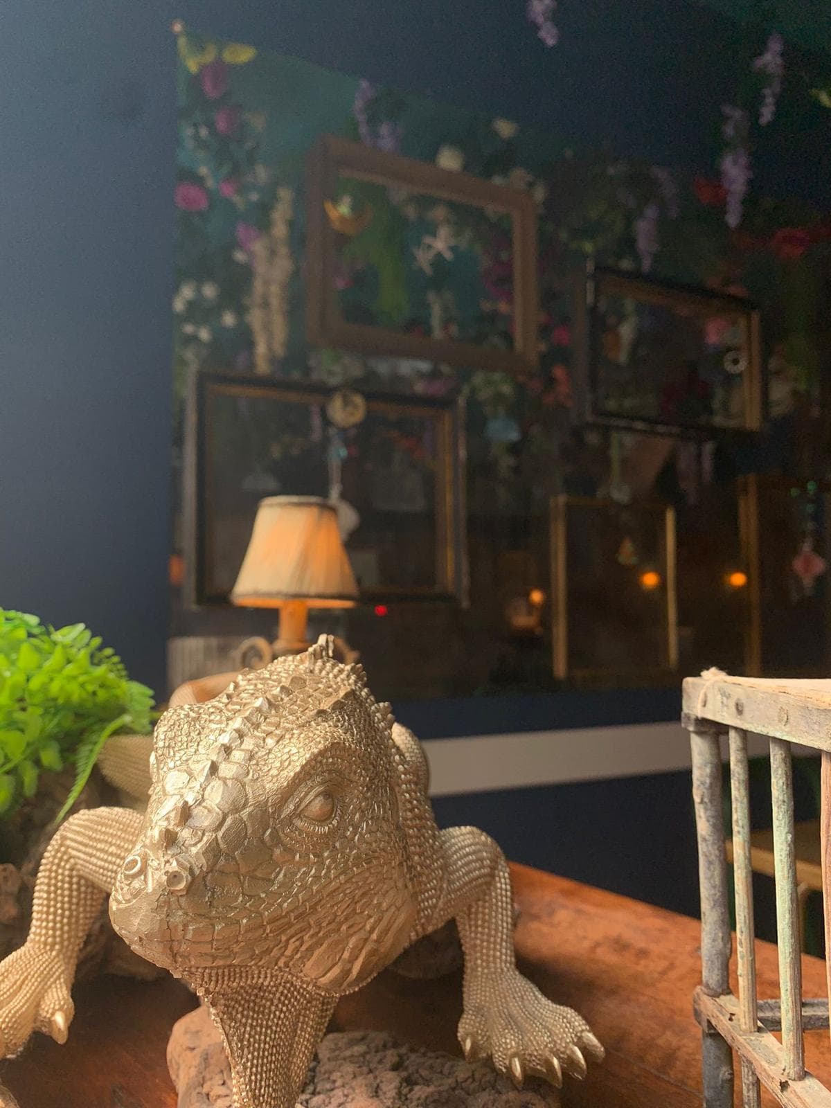 Un'iguana d'ottone su un tavolo di legno, davanti alla parete degli specchi.